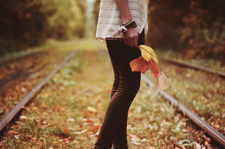woman standing on alley and holding colorful autumn leaves on hands. natural autumn backgroundの写真素材