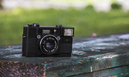 Novopolotsk, Belarus - May 15, 2018: Old camera Elikon is lying on a bench on the background of greeneryの写真素材