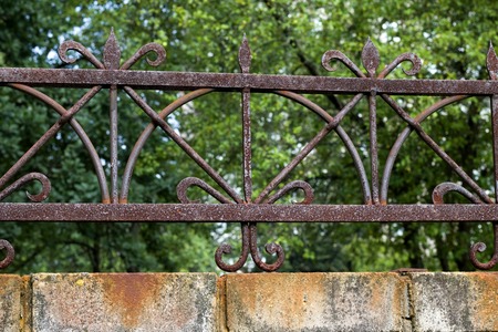 Forged metal grill with rust on the fence in garden