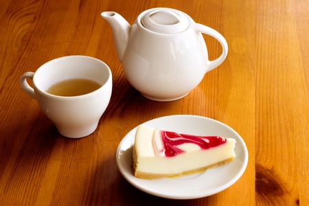 Cheesecake, a cup of tea and a kettle on wooden tableの写真素材