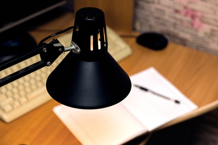 Black lamp above the table with notebook, keyboard and mouseの写真素材