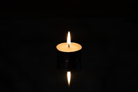 Small candle with reflection close up, isolate on black backgroundの写真素材