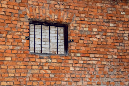 Window with grate on the old red brick wall, abandoned buildingの写真素材