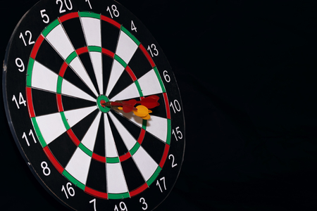 Board for darts and darts in the center on a black backgroundの写真素材