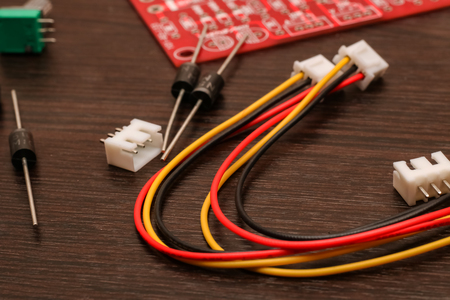 Colored wires, resistor and circuit board close-up on wooden tableの写真素材