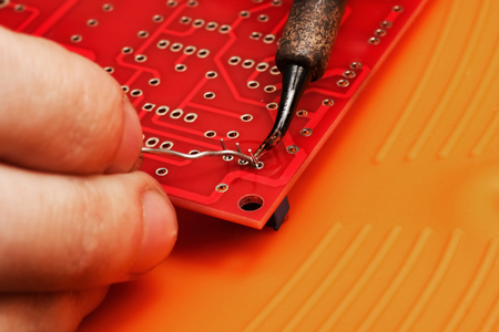 Soldering process on a red printed circuit board close upの写真素材