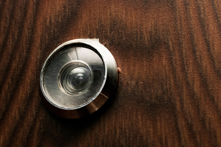 Peephole at the door with a wooden texture close upの写真素材