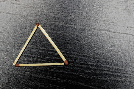 The triangle is made of matches on a black background, copy spaceの写真素材