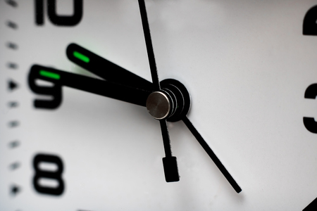 Black hands of a clock on a white dial close up, copy space