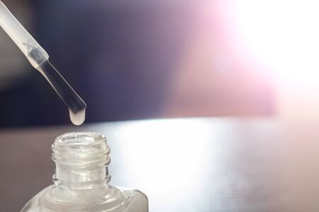 White nail polish and brush for applying manicure on a purple backgroundの写真素材