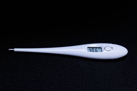 White electronic thermometer with high temperature close up on black backgroundの写真素材