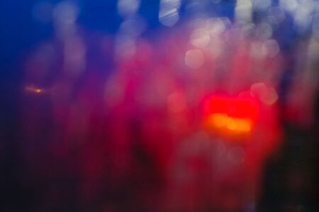 Raindrops and stains on glass at night in the city, blurred backgroundの写真素材