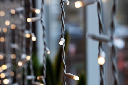 White light bulbs of a garland on a window close up