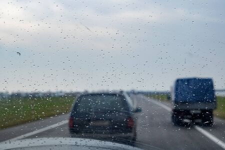 Car glass with raindrops, road with cars, backgroundの写真素材