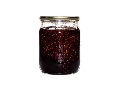 Glass jar with raspberry jam close up isolated on a white background