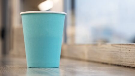 Blue paper cup with coffee on a wooden table, copy spaceの写真素材