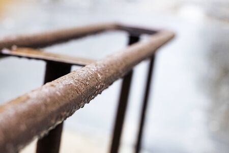 Metal railing with drops of water in the rain close up