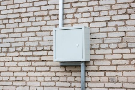 Metal box with electric wires on a brick wall of a house