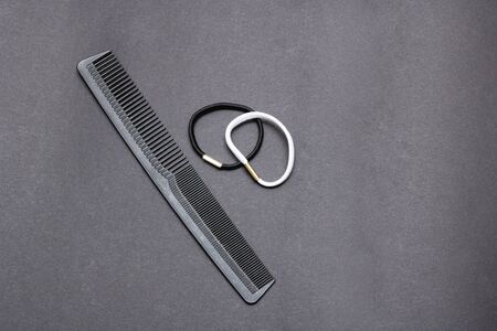 Black elastic for hair and comb on a gray background