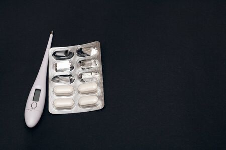 Packing pills and thermometer on a gray background, copy space
