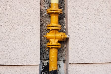 Yellow water pipe on a house wall close upの写真素材