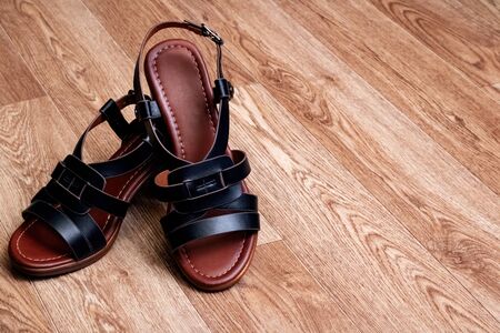 Women's black sandals with straps on woodenbackground close up, copy spaceの写真素材