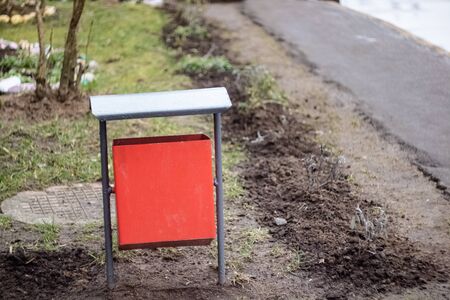Red metal litter bin on the sidewalk close upの写真素材