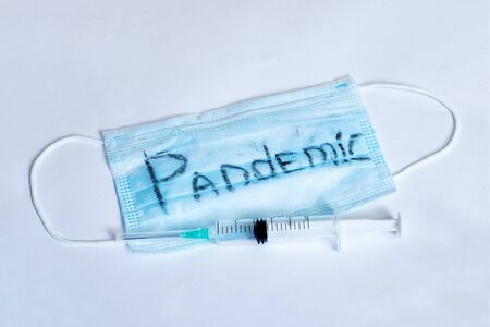 Protective mask with an inscription pandemic and a syringe on gray backgroundの写真素材