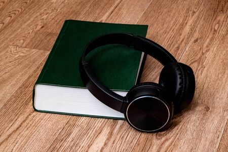 Green paper and headphones on a wooden background close upの写真素材