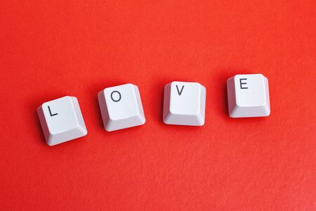 Word love made of white keyboard keys on red background close up