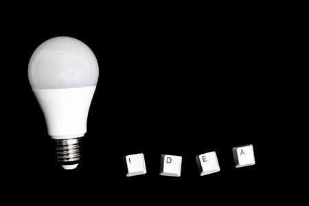 White light bulb and the word idea on a black backgroundの写真素材