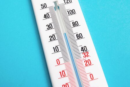 White room thermometer on a blue background close up