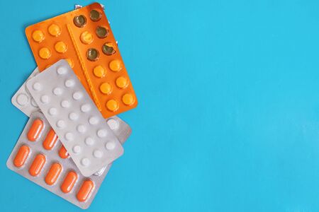 Pile of packs of pills on blue background, copy space