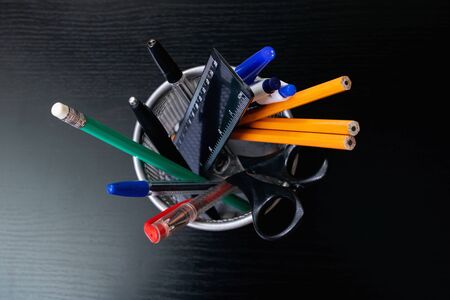 Metal stand with pencils, pens, scissors on wooden tableの写真素材