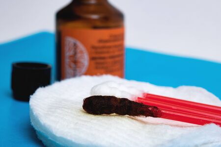 Jar with medical iodine and cotton buds on a blue background macro photoの写真素材