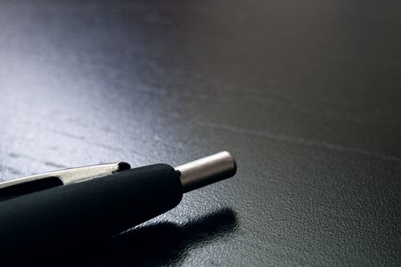Black pen on a black wooden table copy space