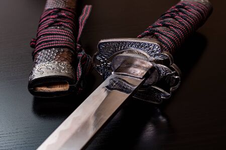 Samurai sword on a black wooden table close upの写真素材
