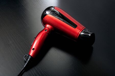 Red hairdryer on a black wooden table close upの写真素材