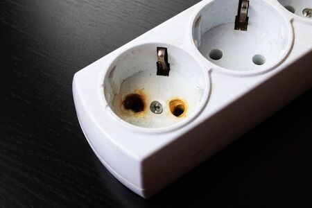Old burnt extension cord on a black background close upの写真素材
