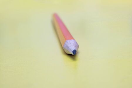 Orange pencil on a yellow background close upの写真素材