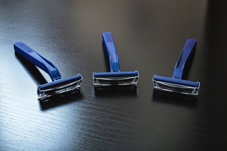 Three blue razors on a wooden background close upの写真素材