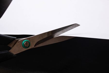 Scissors cut paper on a black background close upの写真素材