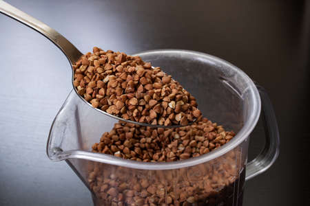 Buckwheat groats in a spoon on black background close upの写真素材