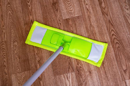 Green mop on a wooden floor close up