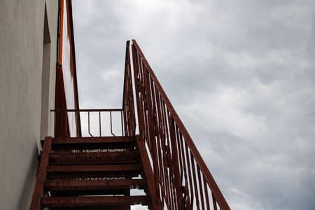 Metal staircase to the roof of the building on the gloomy skyの写真素材