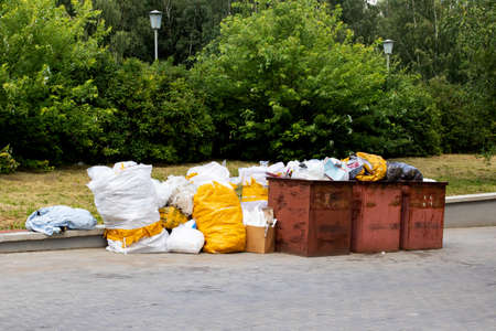 Trash cans and large white garbage bags outdoorsの写真素材
