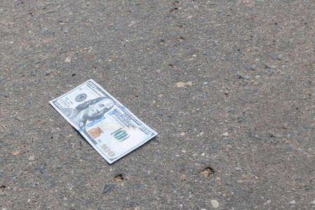 Crumpled one hundred dollar bill on the pavementの写真素材