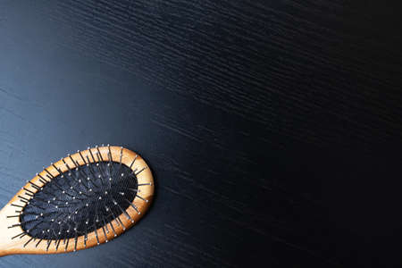 Wooden comb on a black background, copy space