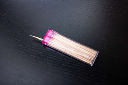 Toothpicks in a plastic box on a wooden table