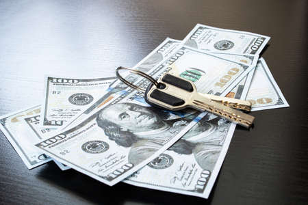 Bunch of keys and dollar bills on a wooden tableの写真素材